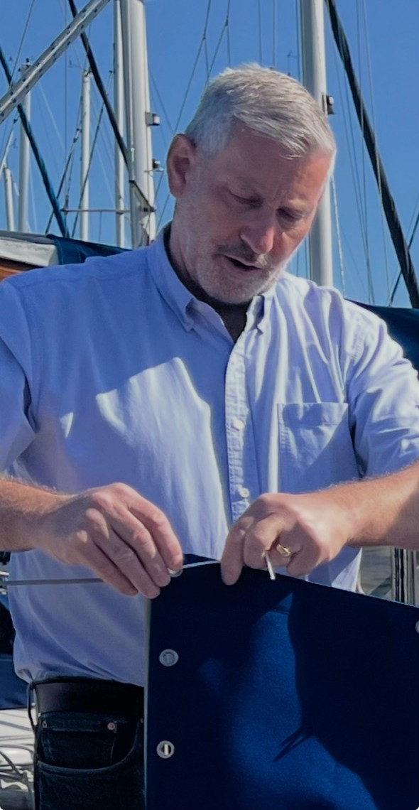 John Bland working on marine canvas and boat-cover details aboard a sailing boat